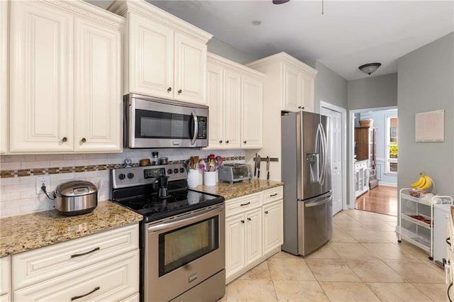 1019 Legacy Walk, Woodstock, GA 30189 - kitchen featuring appliances with stainless steel finishes, light stone counters, light tile patterned floors, and backsplash