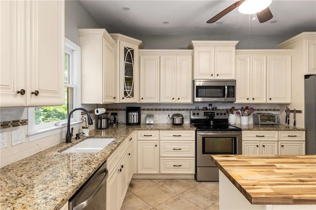 1019 Legacy Walk, Woodstock, GA 30189 - kitchen with stainless steel appliances, a sink, wood counters, decorative backsplash, and a ceiling fan
