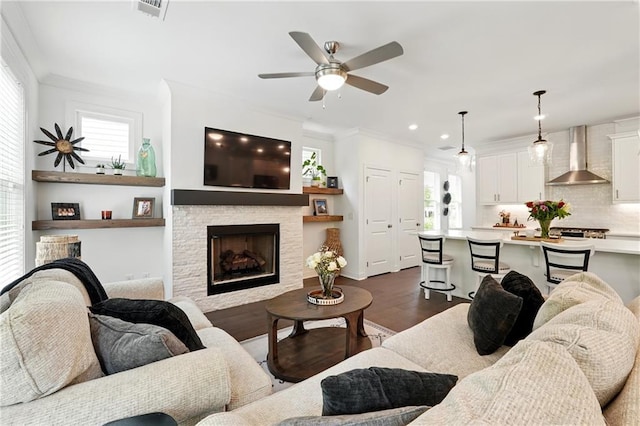 living room featuring ornamental molding, a fireplace, ceiling fan, dark wood-type flooring, and recessed lighting