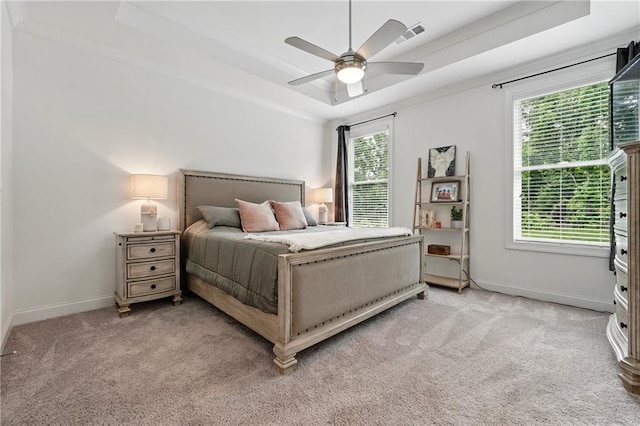 bedroom with a raised ceiling, light carpet, baseboards, and ceiling fan