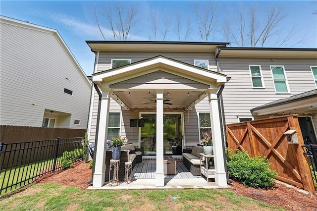 rear view of house featuring ceiling fan, an outdoor living space, a fenced backyard, and a patio area
