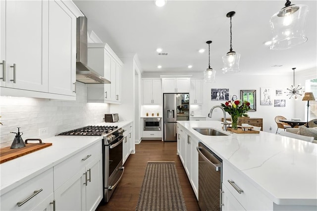 kitchen featuring stainless steel appliances, wall chimney range hood, a sink, dark wood-type flooring, and recessed lighting