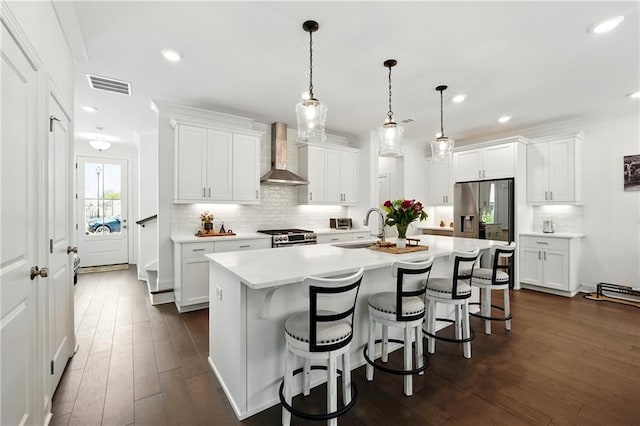 kitchen featuring wall chimney range hood, a sink, appliances with stainless steel finishes, light countertops, and backsplash