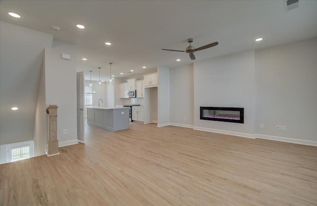 unfurnished living room featuring ceiling fan and light hardwood / wood-style floors