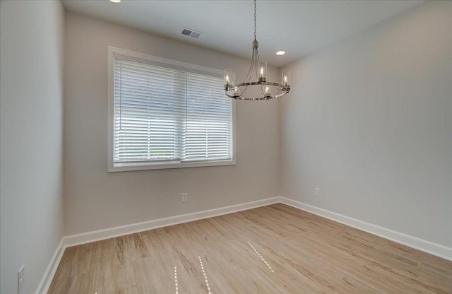 unfurnished room featuring a chandelier and light hardwood / wood-style floors