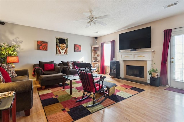 living room featuring ceiling fan, a textured ceiling, and light hardwood / wood-style flooring