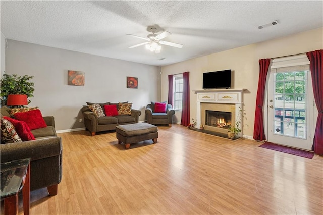 4450 Millenium View Ct, Snellville, GA 30039 - living room featuring light wood-style floors, a ceiling fan, a lit fireplace, and a textured ceiling