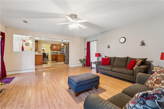 4450 Millenium View Ct, Snellville, GA 30039 - living area featuring light wood finished floors, ceiling fan, a baseboard heating unit, and a textured ceiling