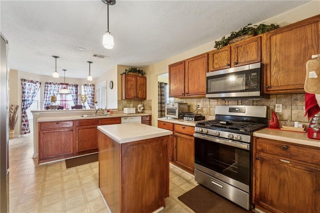 4450 Millenium View Ct, Snellville, GA 30039 - kitchen featuring appliances with stainless steel finishes, a textured ceiling, brown cabinets, light countertops, and a peninsula