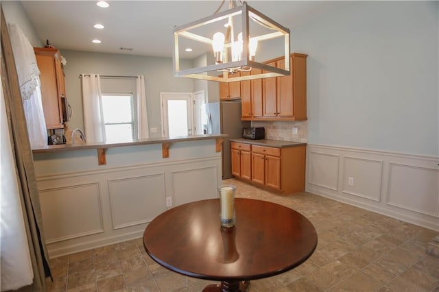 kitchen with recessed lighting, light countertops, a decorative wall, hanging light fixtures, and a chandelier