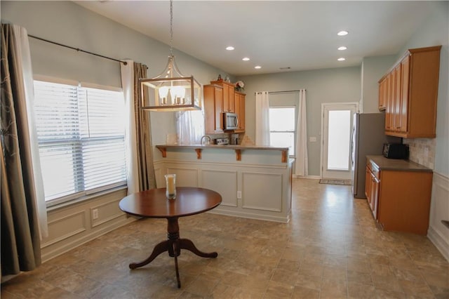 kitchen with appliances with stainless steel finishes, decorative light fixtures, a peninsula, light countertops, and recessed lighting