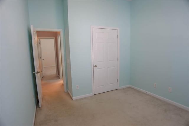 unfurnished bedroom featuring baseboards and light colored carpet