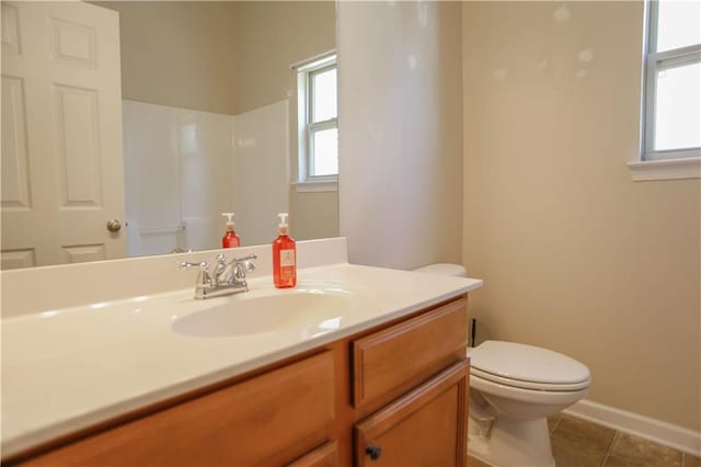 bathroom featuring toilet, tile patterned flooring, vanity, and a healthy amount of sunlight