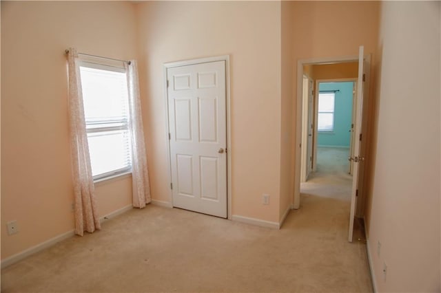 unfurnished bedroom featuring baseboards, multiple windows, and light colored carpet