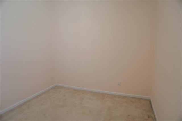 spare room featuring light carpet and baseboards