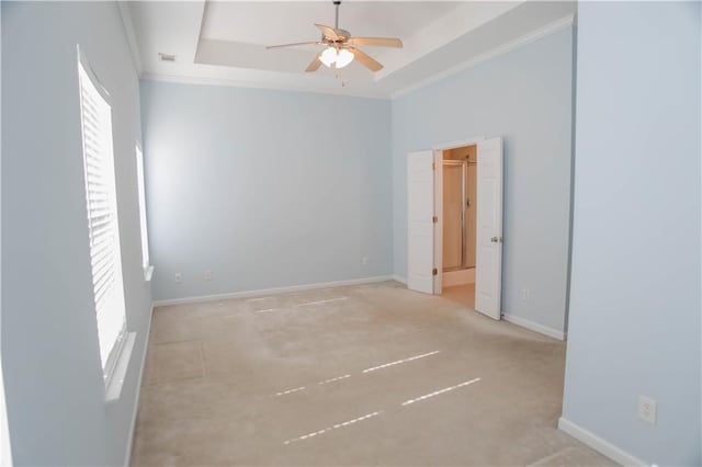 unfurnished room featuring crown molding, a raised ceiling, a ceiling fan, and baseboards