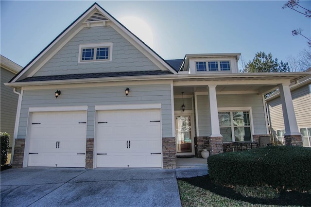 craftsman-style house with a porch, stone siding, driveway, and an attached garage