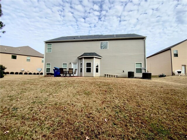 back of property featuring a yard and central air condition unit