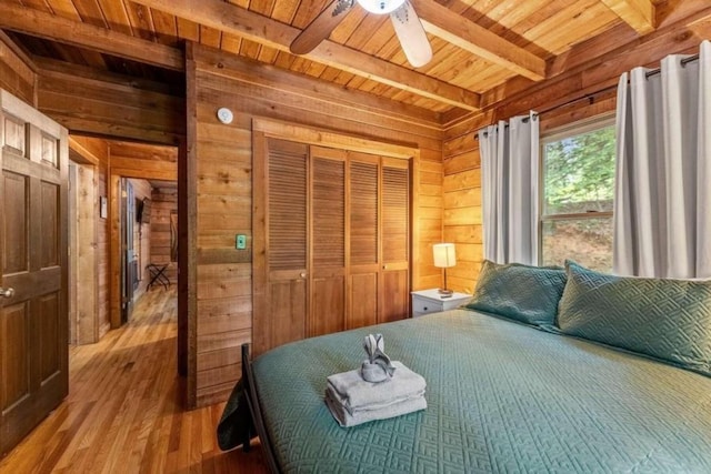 bedroom featuring hardwood / wood-style floors, wood walls, ceiling fan, beamed ceiling, and wood ceiling