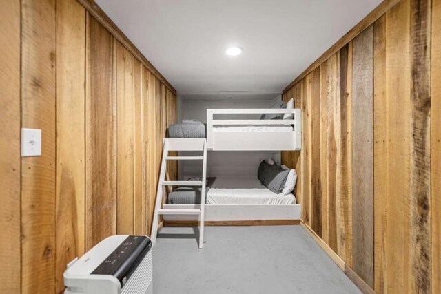 unfurnished bedroom with wood walls and concrete floors