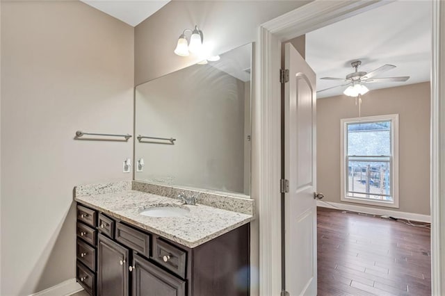 bathroom with a ceiling fan, baseboards, wood finished floors, and vanity