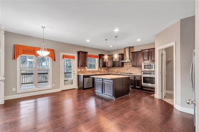 kitchen with backsplash, appliances with stainless steel finishes, dark wood-type flooring, dark brown cabinets, and wall chimney exhaust hood