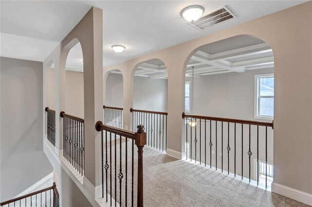 hallway with coffered ceiling, beam ceiling, and carpet