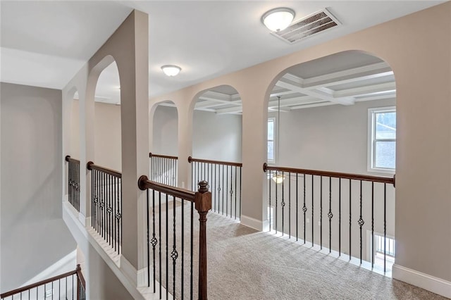 corridor featuring coffered ceiling, carpet flooring, visible vents, baseboards, and beam ceiling