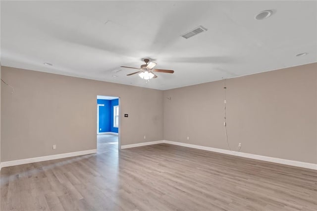 unfurnished room featuring light wood-style floors, baseboards, visible vents, and a ceiling fan