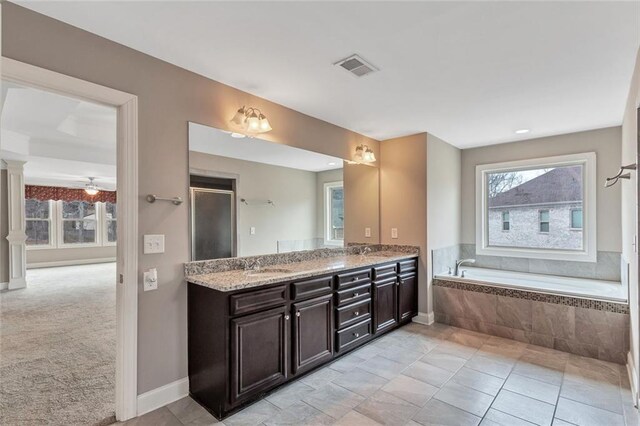 bathroom with ceiling fan, plenty of natural light, tiled bath, and vanity