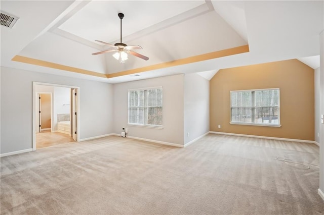 interior space featuring a raised ceiling, vaulted ceiling, light carpet, and ceiling fan