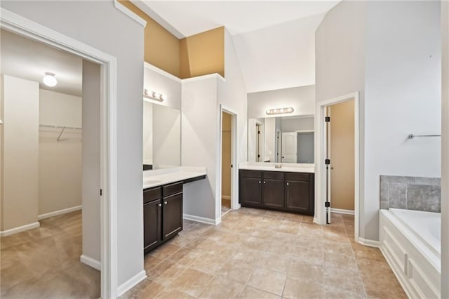 bathroom with tile patterned flooring, vanity, vaulted ceiling, and a washtub