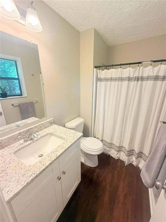 2661 Throatlatch Ln SW, Marietta, GA 30064 - full bathroom with wood finished floors, a textured ceiling, vanity, toilet, and a shower with shower curtain