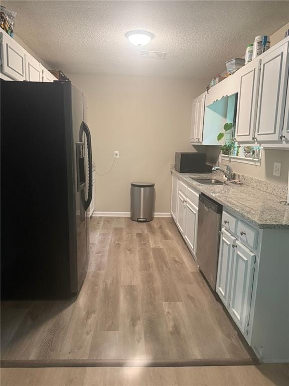 2661 Throatlatch Ln SW, Marietta, GA 30064 - kitchen with stainless steel appliances, a sink, a textured ceiling, light wood finished floors, and light stone counters