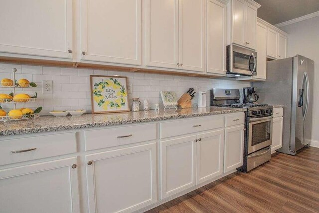 kitchen featuring appliances with stainless steel finishes, tasteful backsplash, white cabinetry, and light stone counters