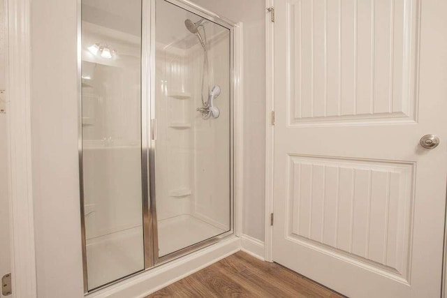 bathroom with a shower with shower door and hardwood / wood-style flooring