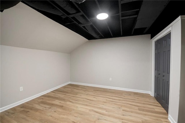 additional living space with light hardwood / wood-style floors and vaulted ceiling