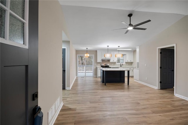 kitchen featuring white cabinetry, a center island, ceiling fan, sink, and pendant lighting