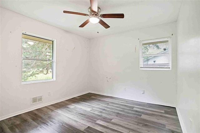 unfurnished room featuring plenty of natural light, wood finished floors, a ceiling fan, and baseboards