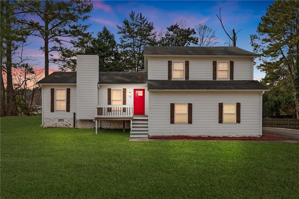 split level home featuring crawl space, a front yard, and a chimney