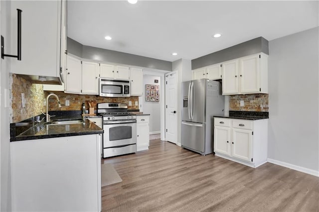 kitchen with appliances with stainless steel finishes, light wood-type flooring, white cabinets, and sink