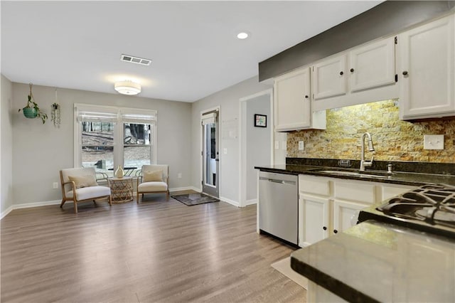 kitchen with dishwasher, decorative backsplash, white cabinets, light hardwood / wood-style flooring, and sink