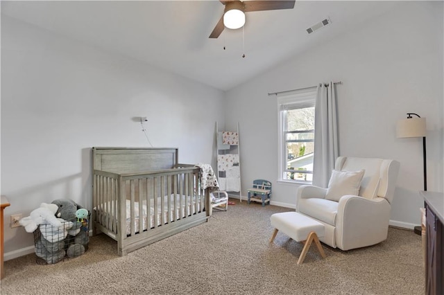 carpeted bedroom with a crib, ceiling fan, and vaulted ceiling