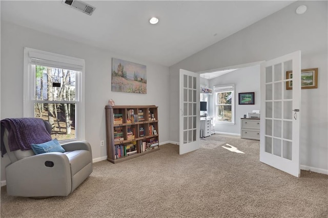 living area with lofted ceiling, french doors, and light colored carpet