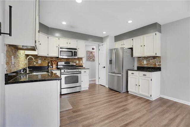 kitchen featuring appliances with stainless steel finishes, white cabinetry, light hardwood / wood-style floors, and sink