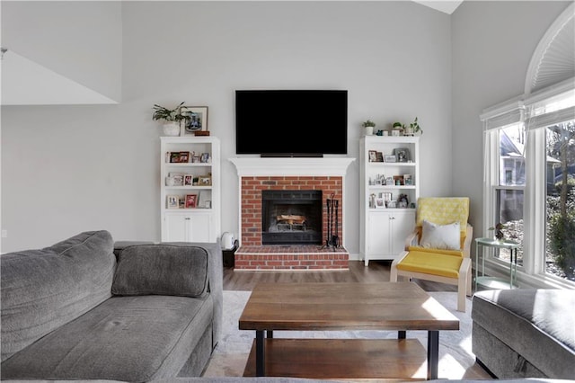 living room with a brick fireplace and hardwood / wood-style floors