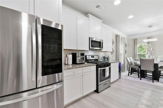 140 Canyons Ct, Hampton, GA 30228 - kitchen featuring appliances with stainless steel finishes, white cabinets, light stone countertops, light wood finished floors, and recessed lighting