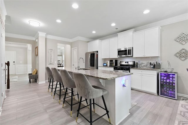 140 Canyons Ct, Hampton, GA 30228 - kitchen featuring stainless steel appliances, a breakfast bar, an island with sink, ornamental molding, and white cabinetry