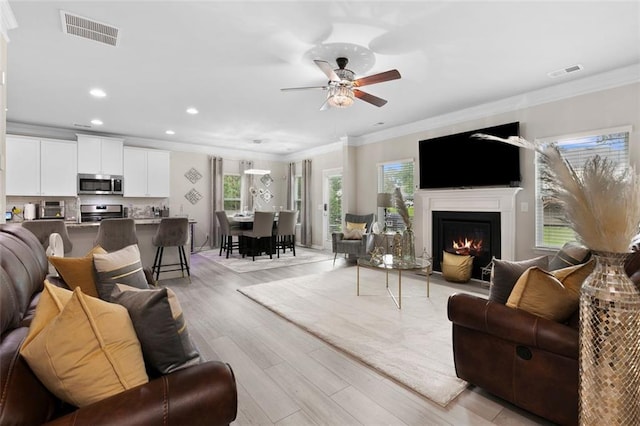 140 Canyons Ct, Hampton, GA 30228 - living room with light wood-style floors, ornamental molding, a ceiling fan, recessed lighting, and a warm lit fireplace