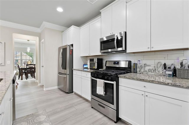 140 Canyons Ct, Hampton, GA 30228 - kitchen featuring stainless steel appliances, crown molding, white cabinetry, tasteful backsplash, and light stone counters